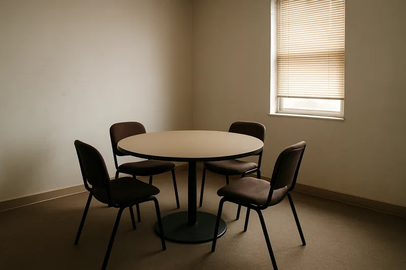 Four empty chairs around a plain round table — complaints and dispute resolution, Townsville. Illustrative example.
